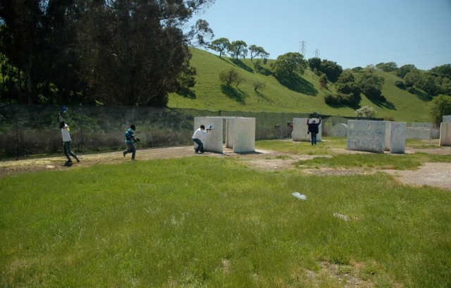 jugando al paintball en un campo lleno de obstaculos